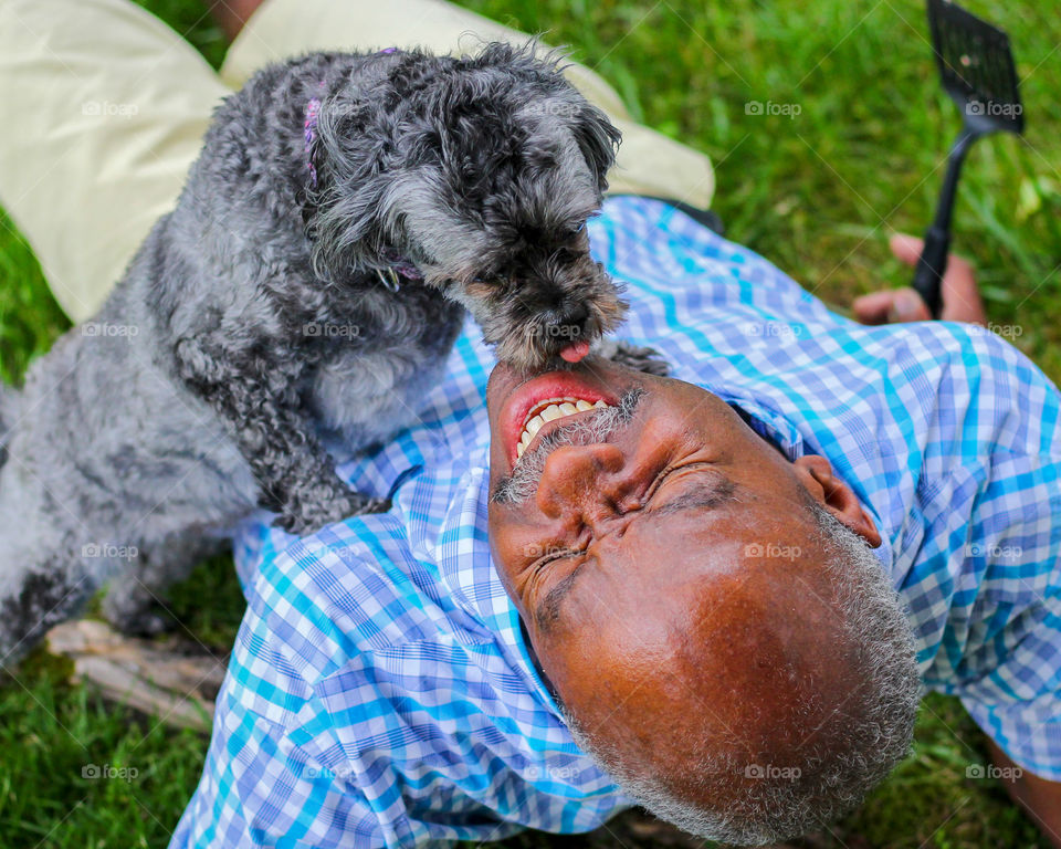 Man laughing as dog picks his face