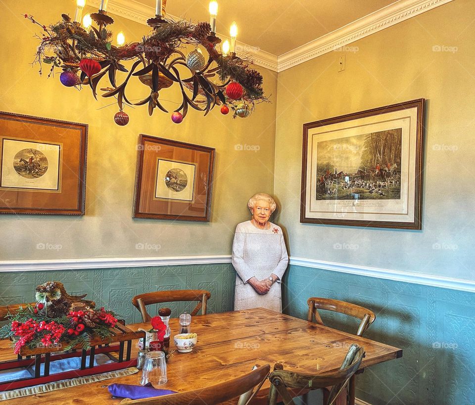 Cardboard cutout of the Queen in the corner of a room