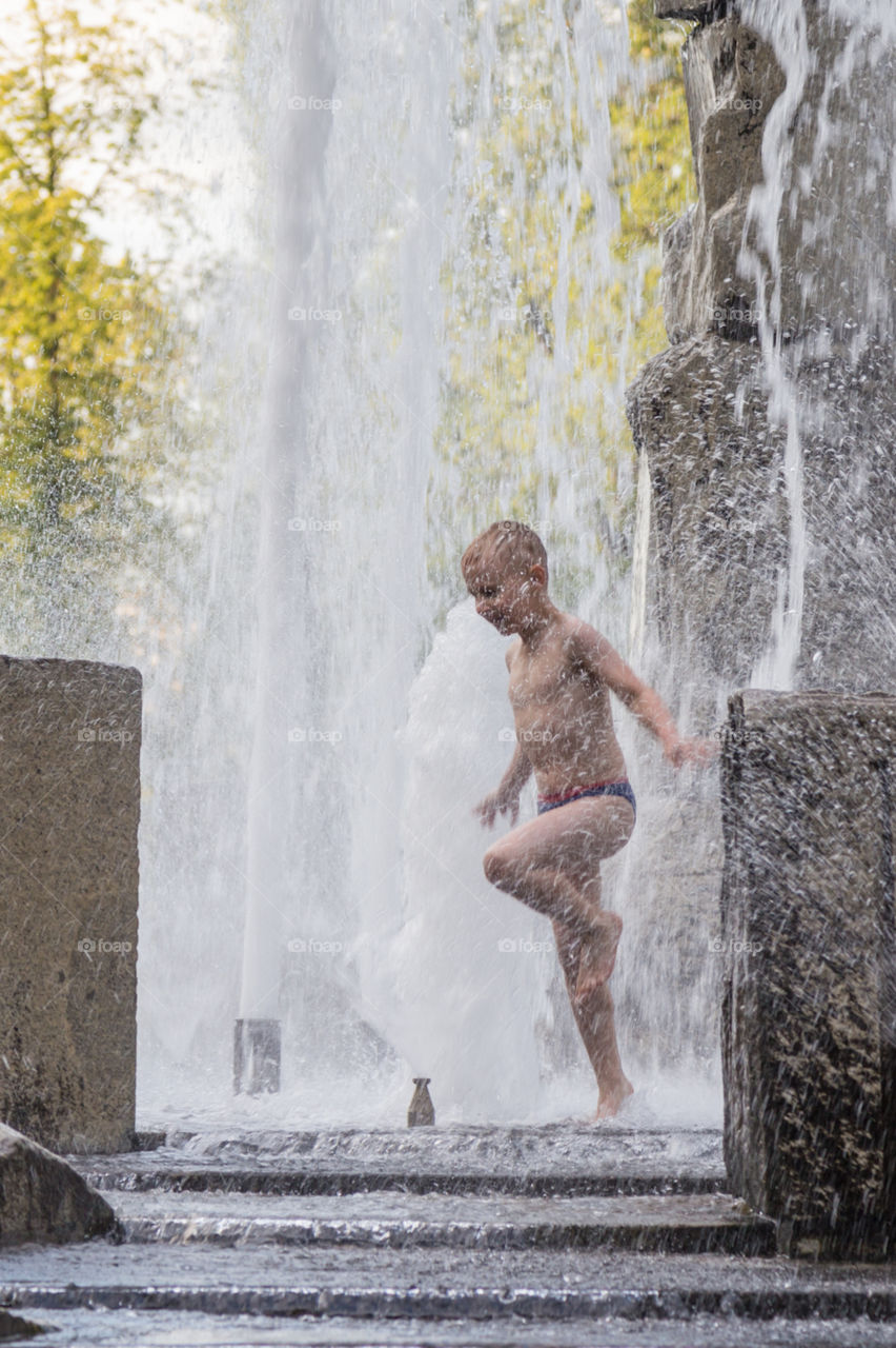 a boy playing in fountain