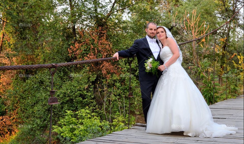 Newly wed couple standing on wooden bridge