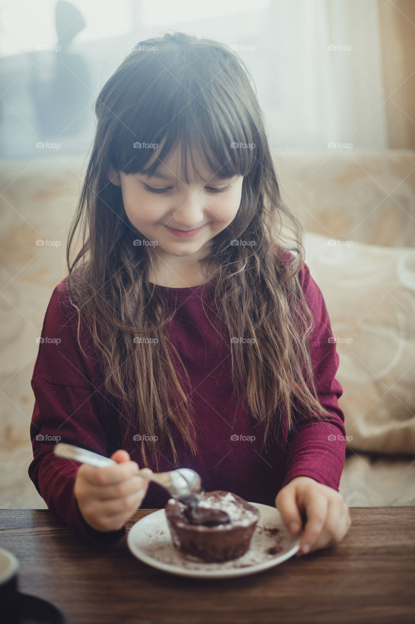Little girl eating the chocolate muffin
