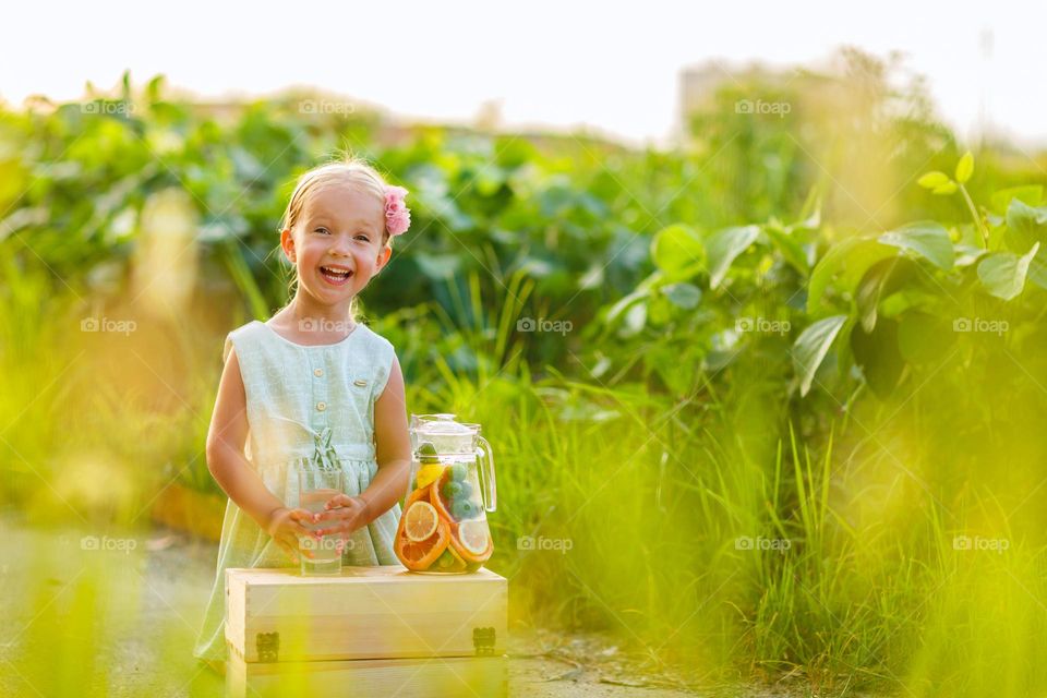 Happy little Caucasian girl with blonde hair smiling outdoor at summer day 