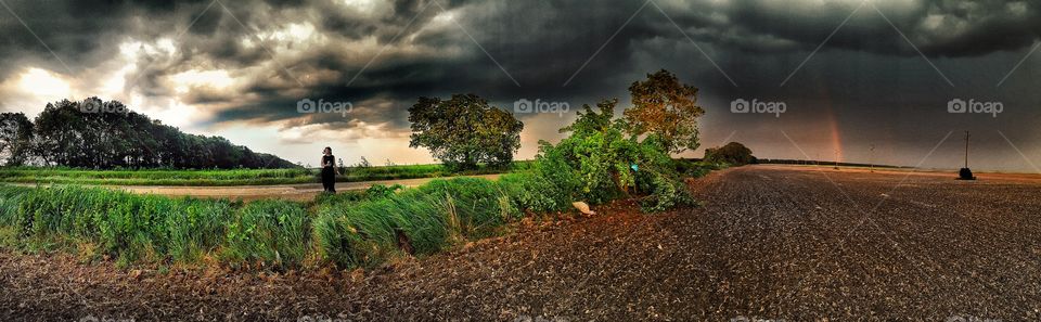 Distant view of a woman standing against storm cloud