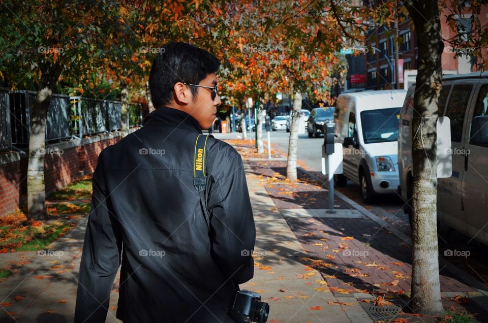 A guy walking along downtown during autumn. 