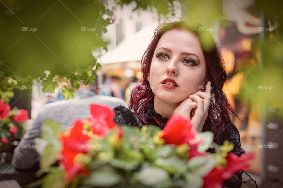 Young gorgeous redheaded woman siting in an outdoor cafe dressed in retro fashion clothes.