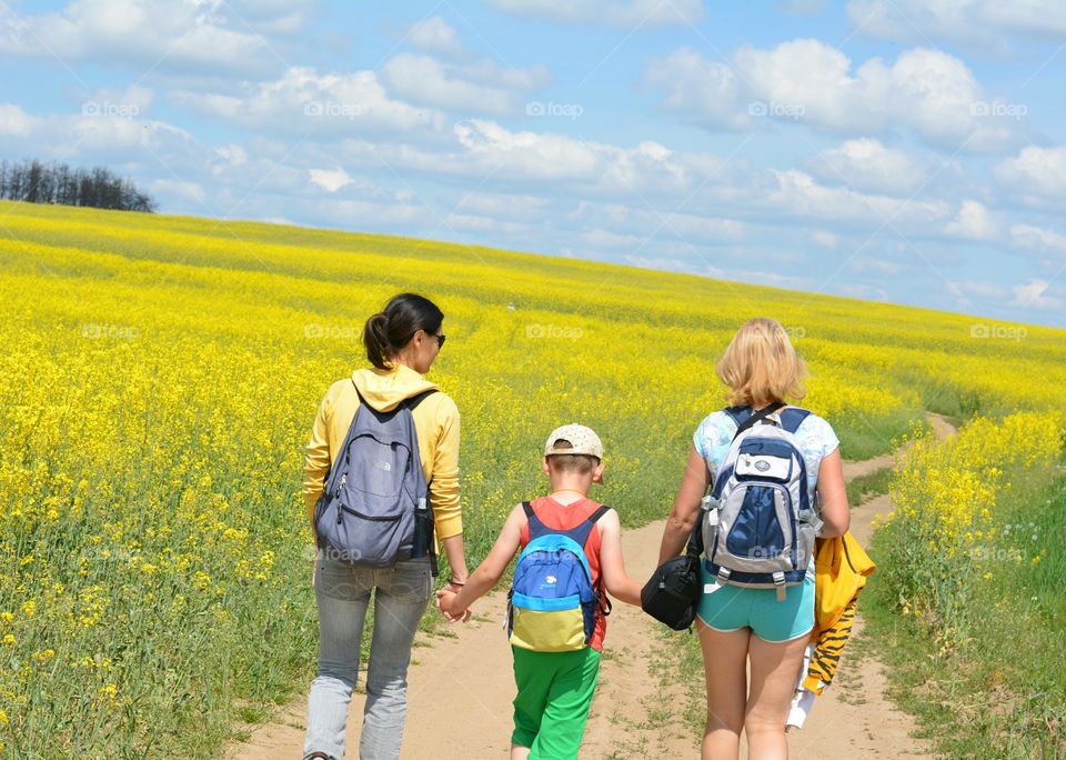 family walking on a road rapeseed yellow field summer travel