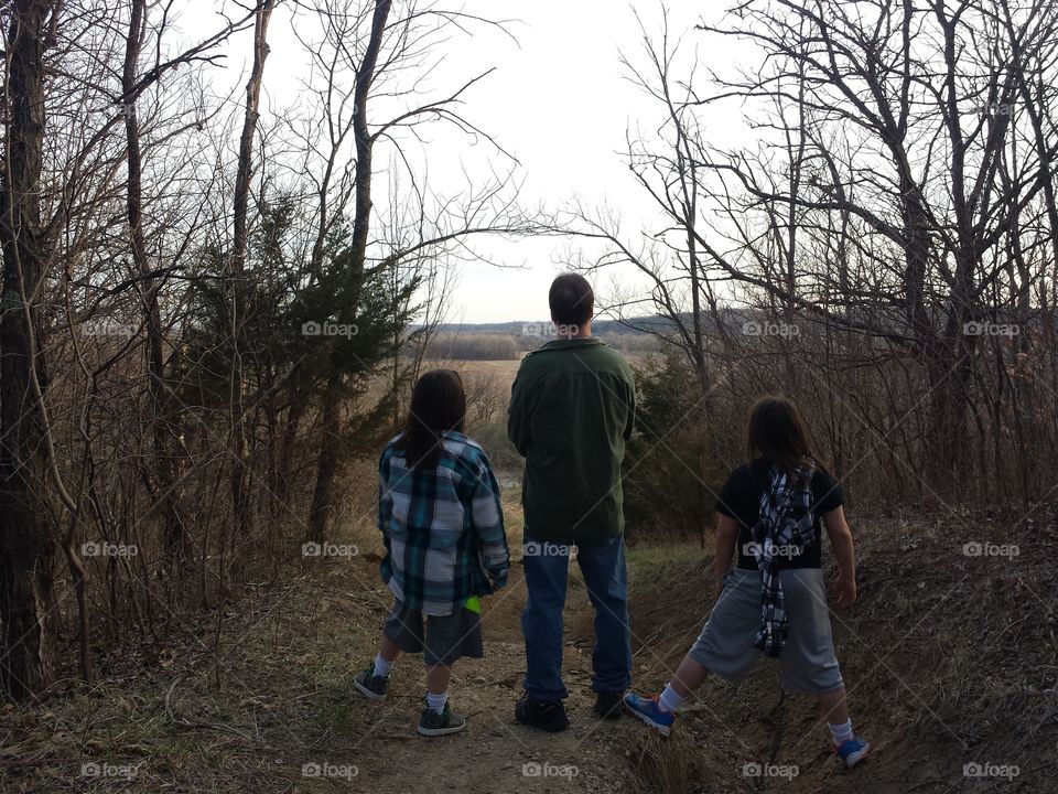 Rear view of man with girls standing near bare trees