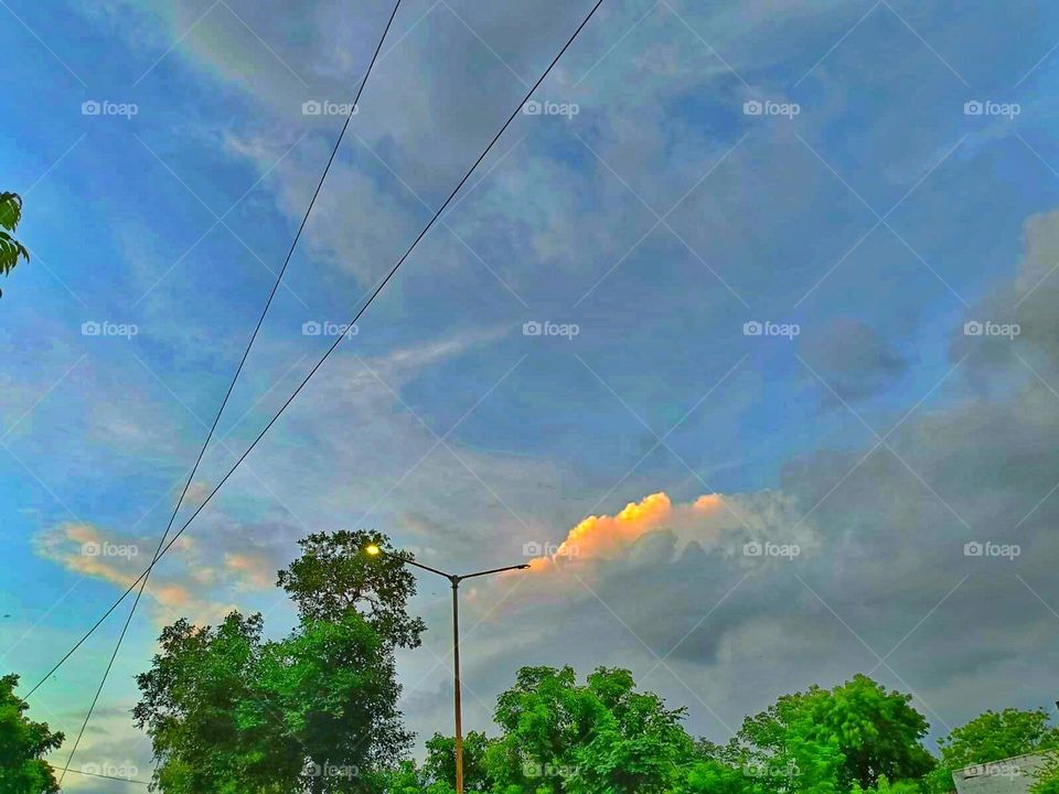 It seems like you're enjoying the view of the intersection with the street lights on a cloudy day. It must have a unique vibe with the cloudy sky in the background.