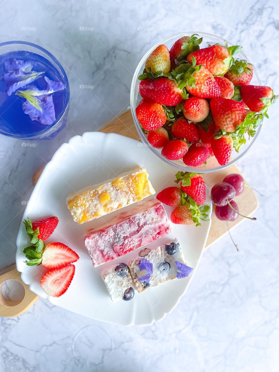 Frozen yogurt bark and some fresh strawberries at the side. Top view. 