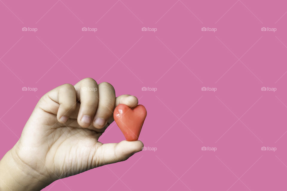 Hand holding a red candy shape heart on a pink background with clipping path for Valentine Day.