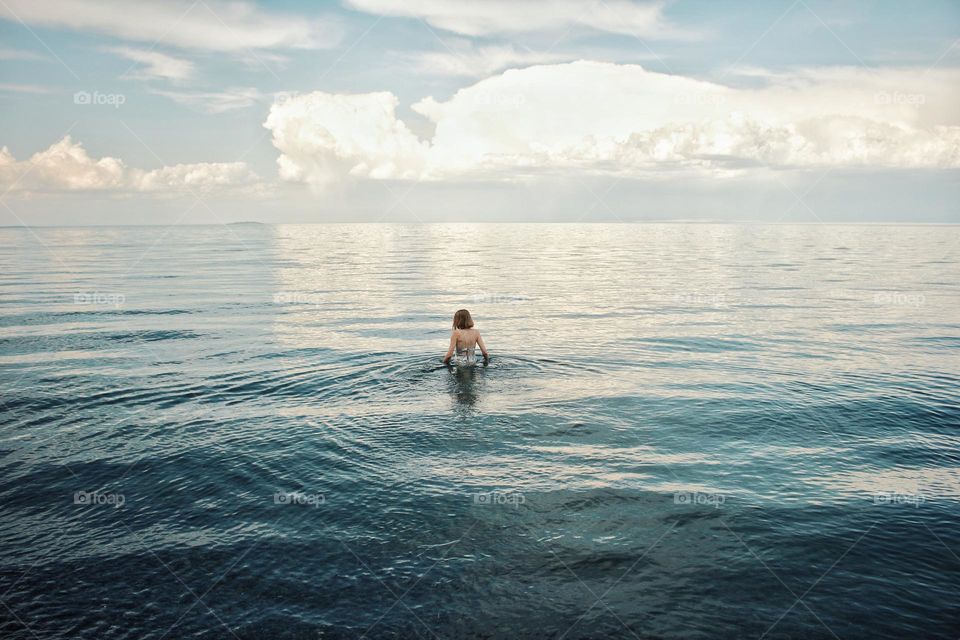 Girl bathes in the lake at sunset
