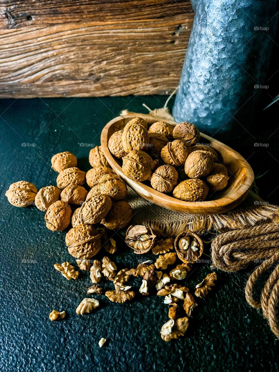 Walnuts in bowl and scattered on top of a black textured table