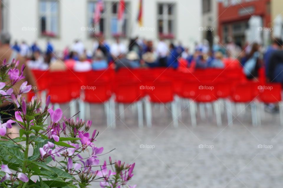 Many people sit on red chairs at an outdoor concert