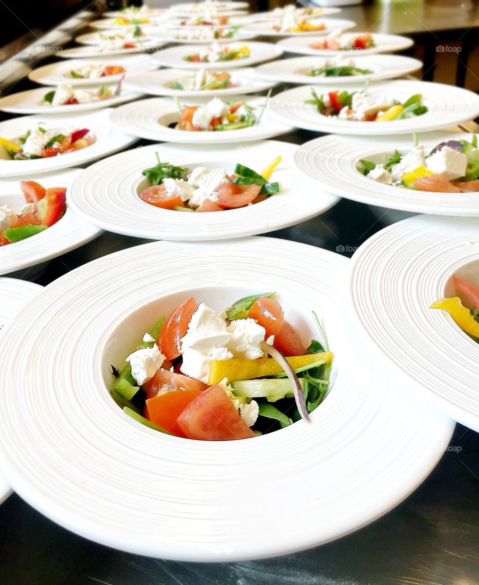 A dozen of fresh salad portions in the white plates
