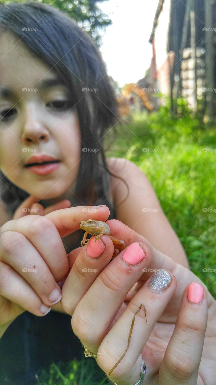 Woman hand holding frog with her daughter