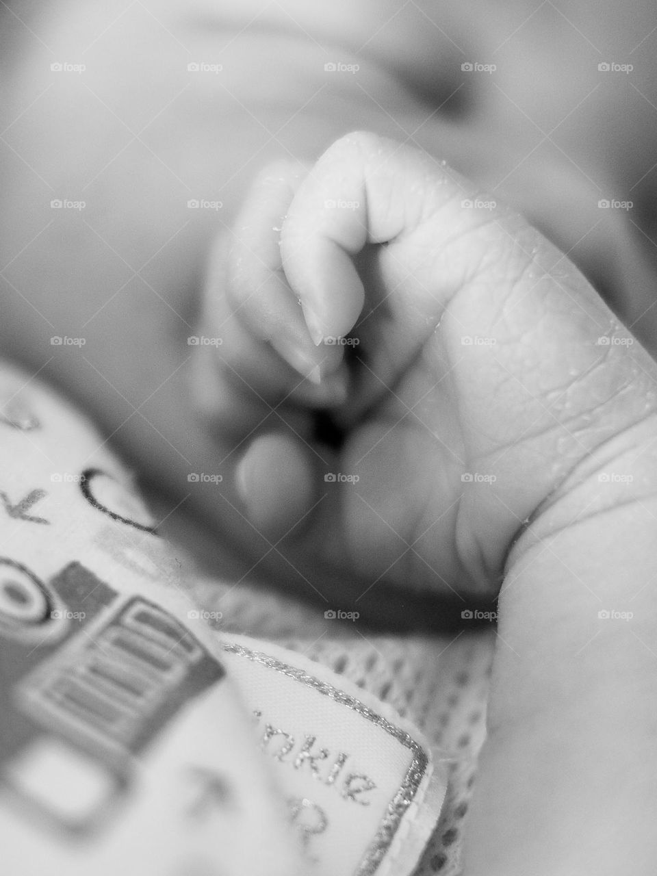 Baby hands closeup on a white background. Baby is sleeping. Newborn boy sleeping with arms under his mouth.