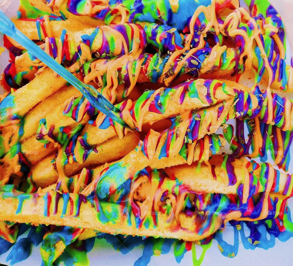 French fries with rainbow-colored cheese sauce.