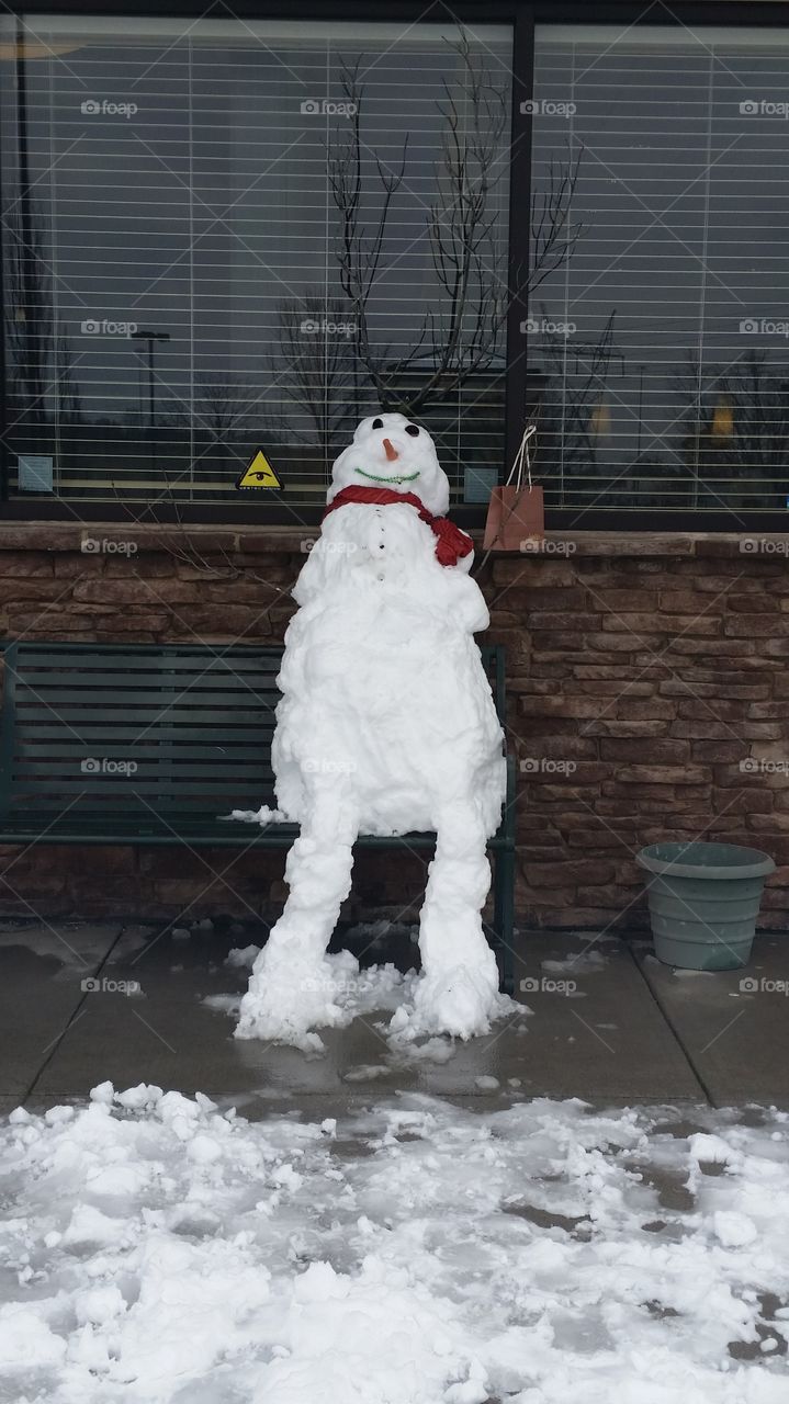 Snowman with legs sitting on a bench