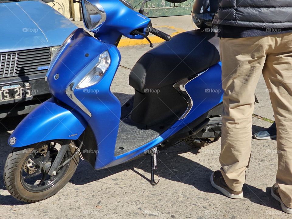 A metallic blue scooter could be your best option for your commute. It's less expensive than a motorbike and has a smaller footprint.