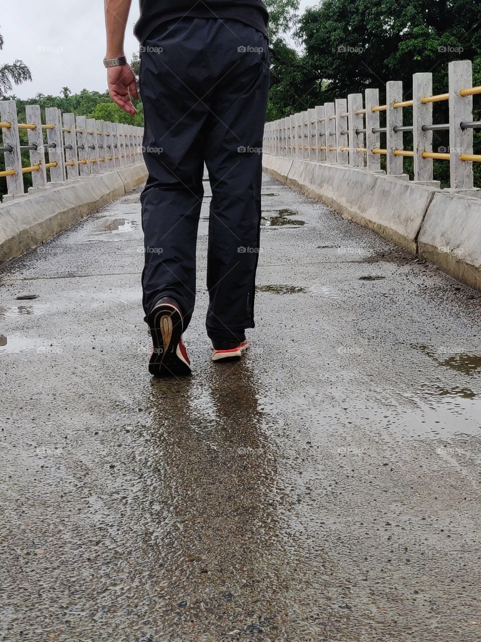 man walking over a bridge on a rainy day. The smart way of moving from A to B