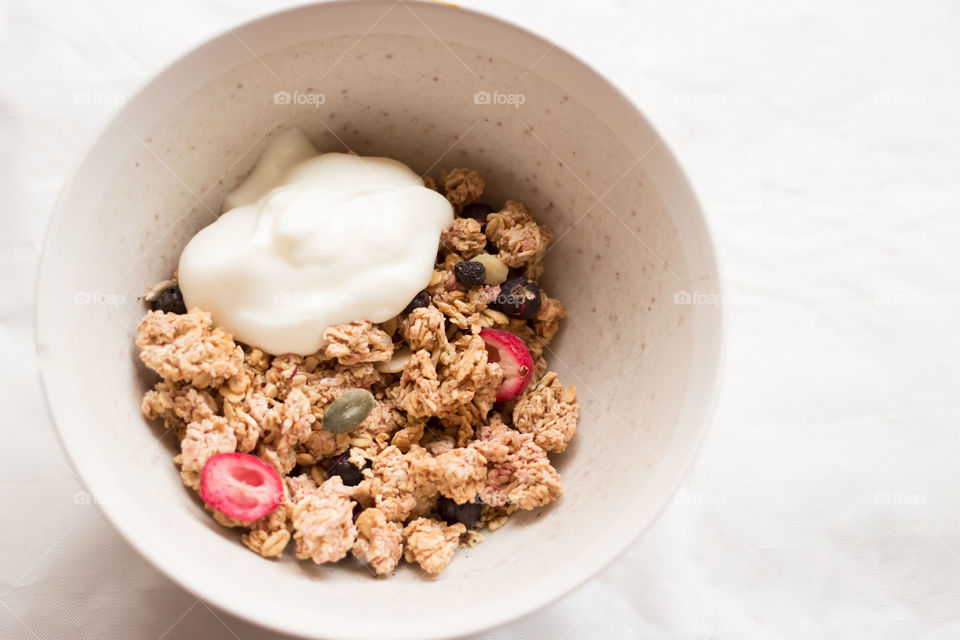 Granola and yogurt in bowl . Granola and yogurt in bowl with fruit on white background 