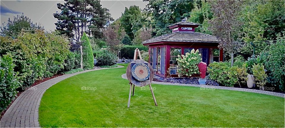 Outside in the garden of the house of an acquaintance of my sister in „Bavaria“, Sputh Germany. She has recently taken to shooting a bow and arrow and my sister’s husband is teaching her and her husband. 2022. Hypnotic Productions