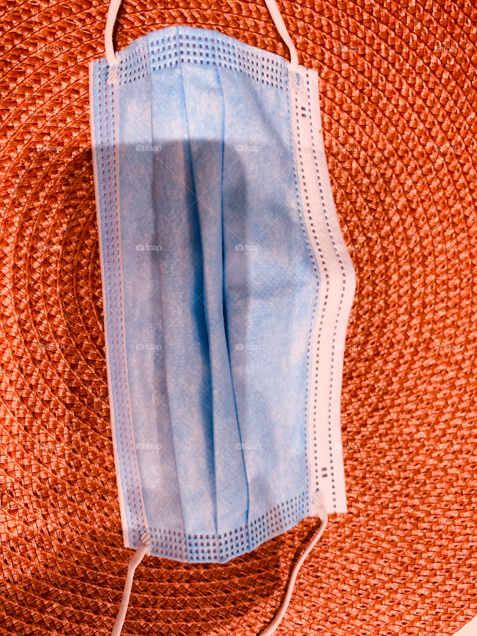 A light blue face mask on an orange finely coiled table tile. Removing mask at the restaurant to eat in the pandemic.