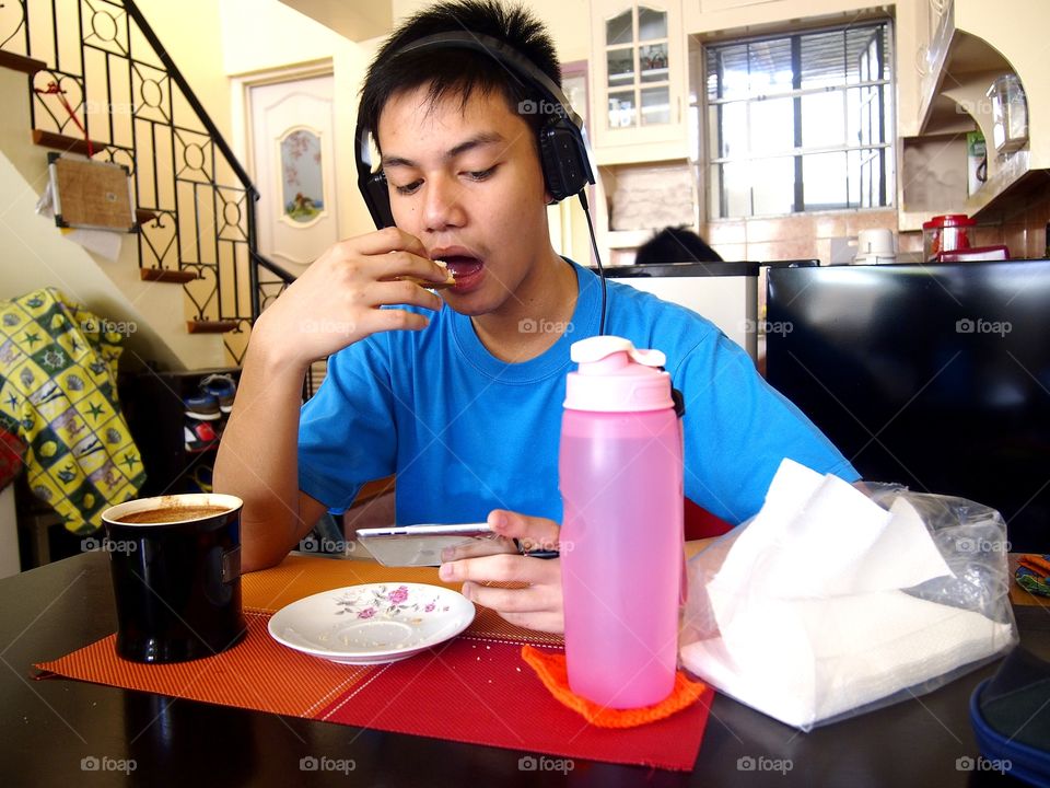young teen eating snack while watching on a mobile device