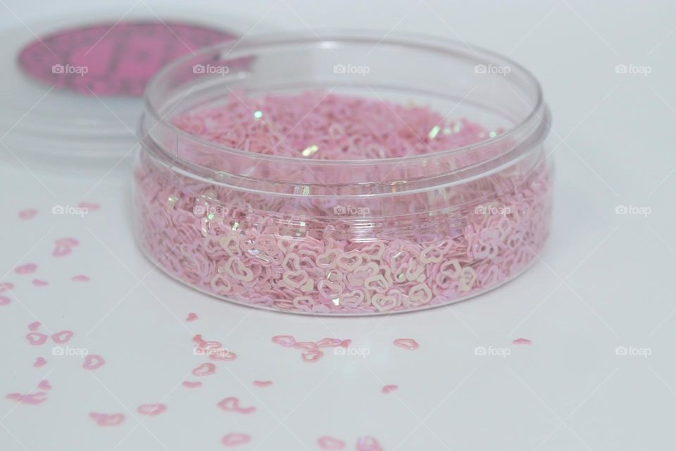 A round plastic container of pink glittery love hearts 💕