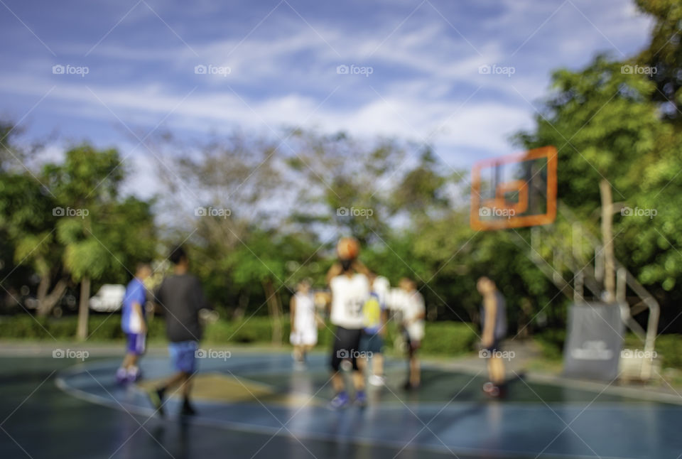 Blurry image of elderly men and teens playing basketball in the morning at BangYai Park , Nonthaburi in Thailand.