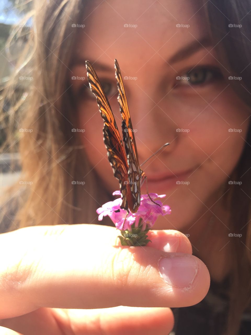 Close-up of woman holding butterfly on flower