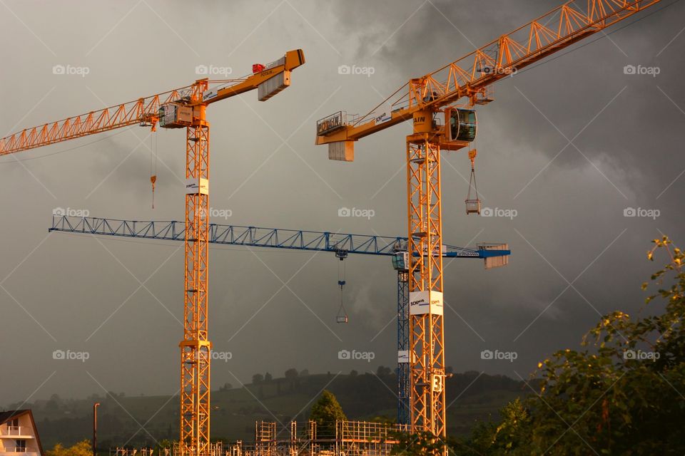 View of cranes against stormy clouds