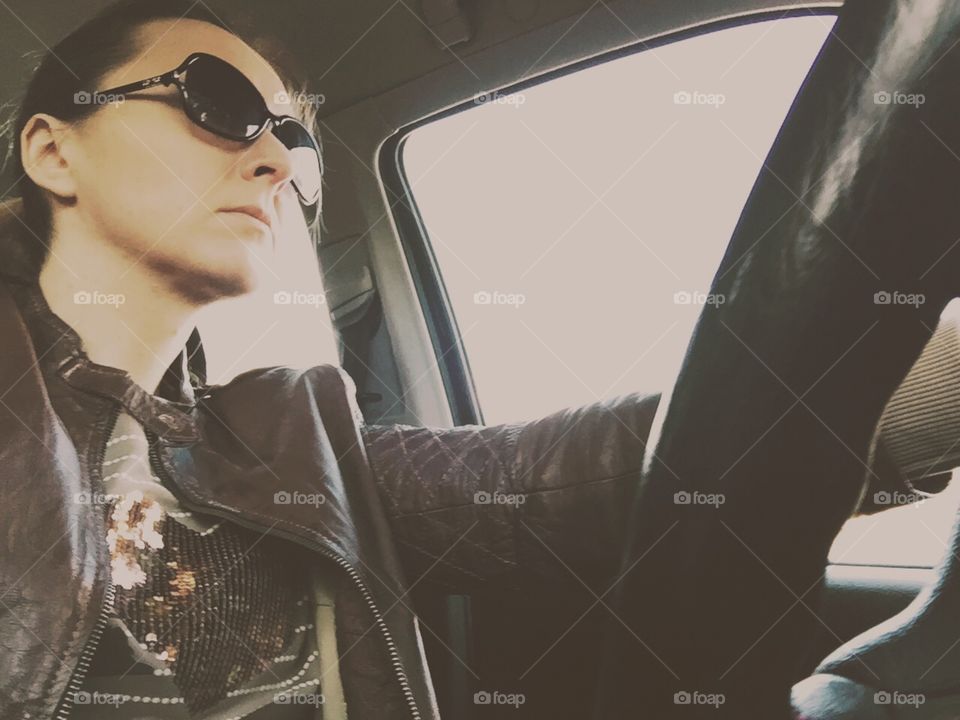 Rocking hard. Woman in sunglasses and leather jacket driving, low angle
