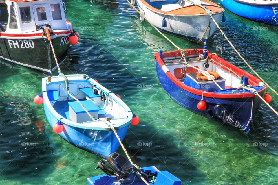 Fishing Boats. Colourful fishing boats moored together in a harbour with emerald green sea below.