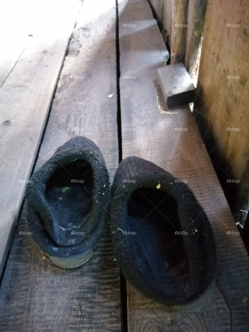 Old black uggs trampled on the floor of untreated boards