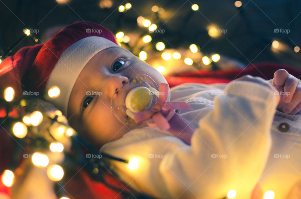 Close-up of a baby wearing christmas cap and pacifier in mouth
