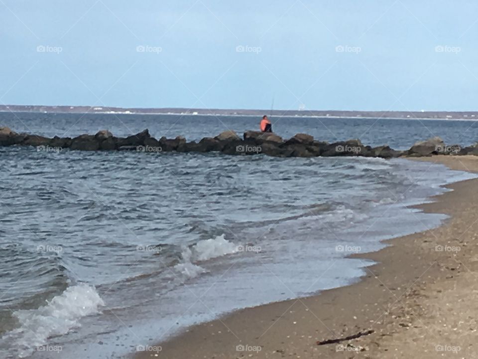 Waves crashing on the beach with fisherman in background.