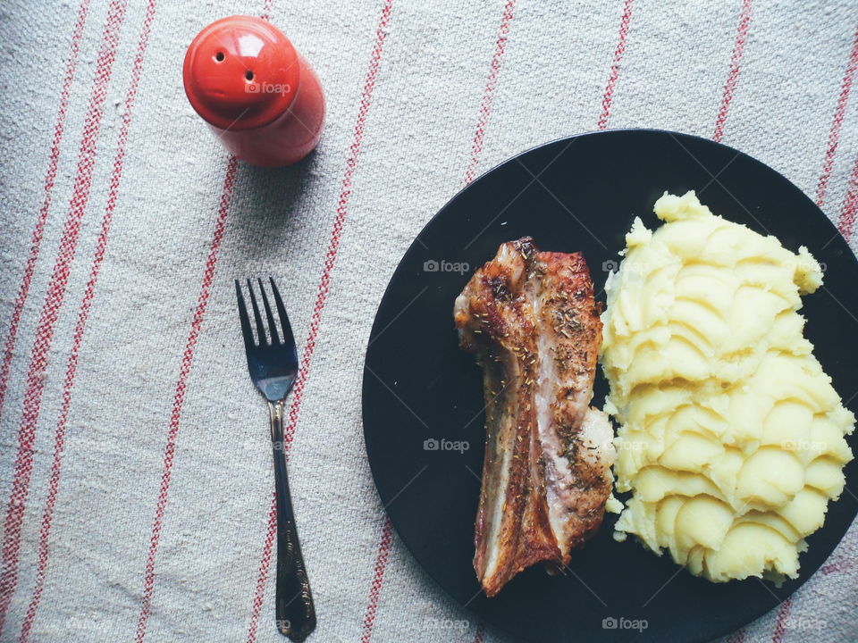 grilled pork ribs,potato puree on a black plate