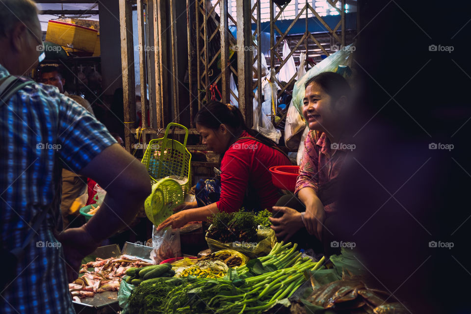 Woman smiling at passing by customers in Asian market