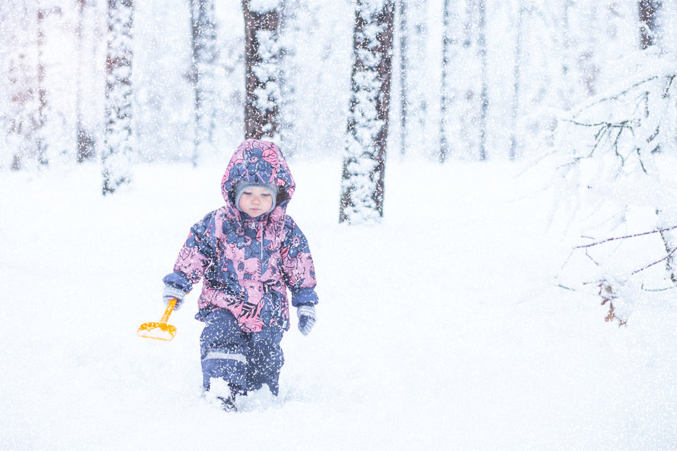 baby walks through the snowy forest in winter