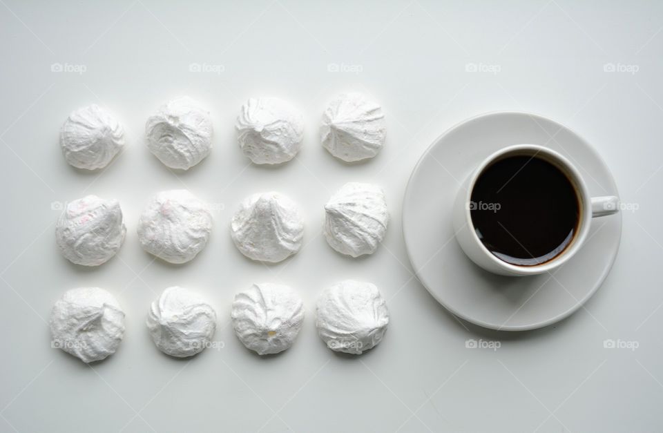 cup of coffee with sweet sugar meringues on a white top view background