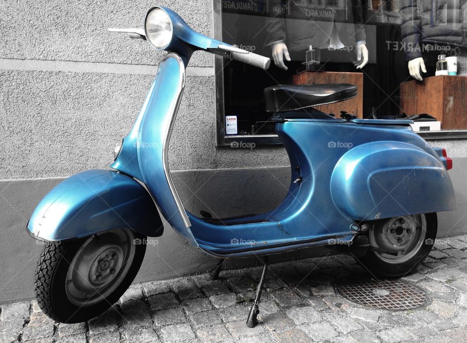 Blue vespa in the city.