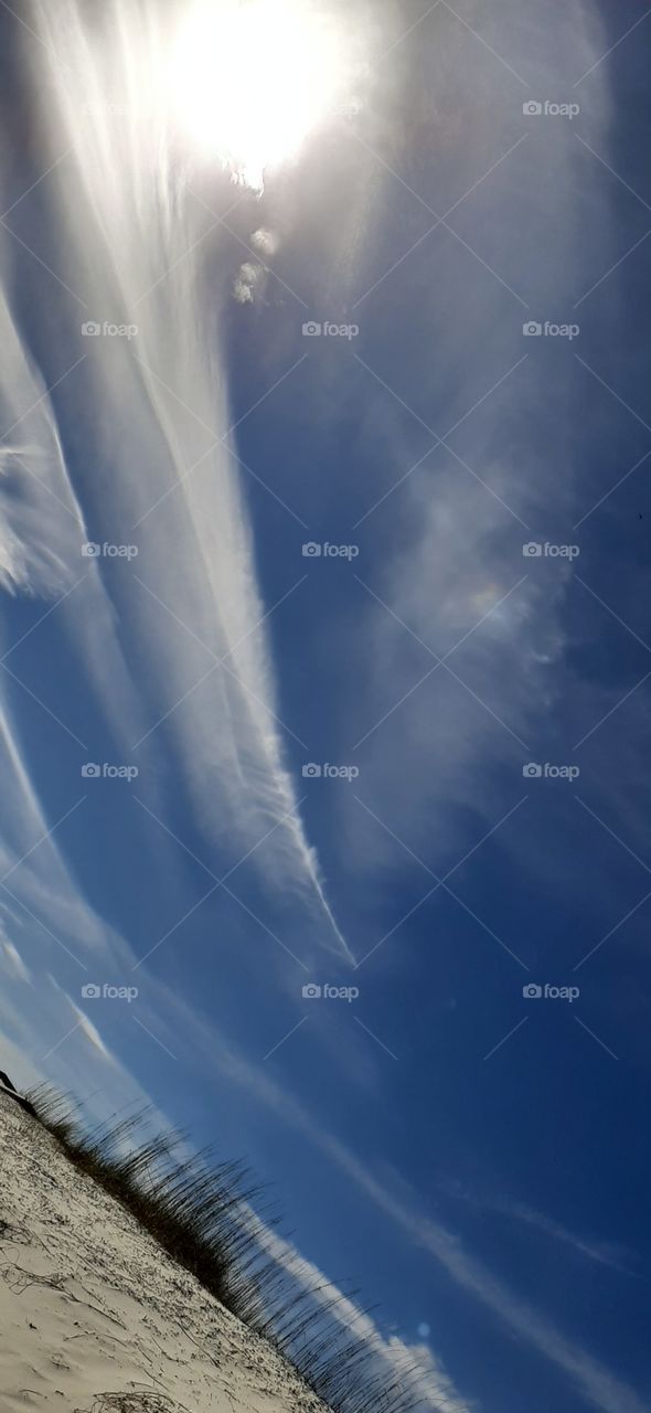 clouds over the beach sea boats in background