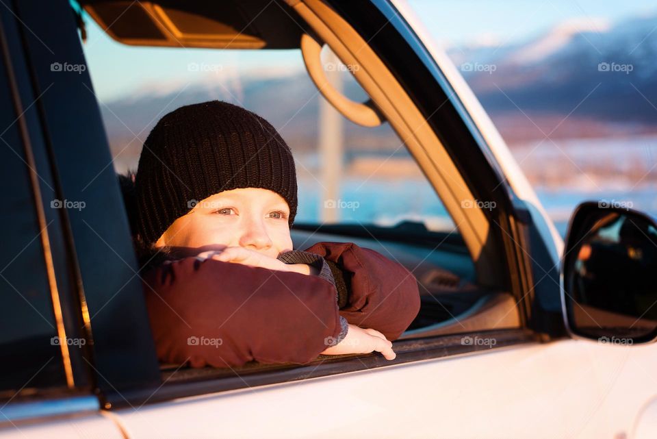 Boy looking out the car window in winter