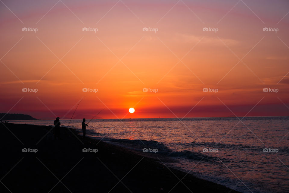 Silhouette of fishermen at sea during sunset