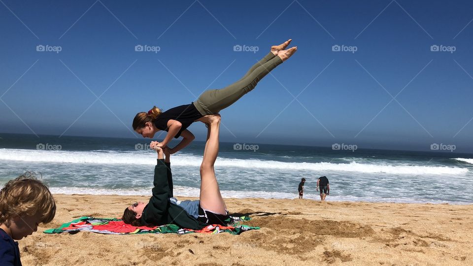 Two girls doing poses in the air at the beach