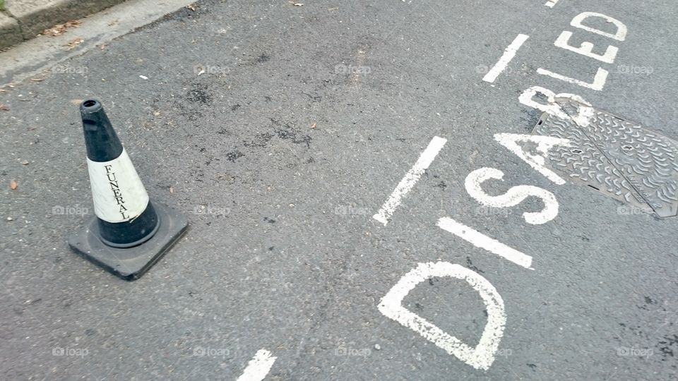 Disabled parking bay marked in white on Station Road, Finchley, with black and white cone
