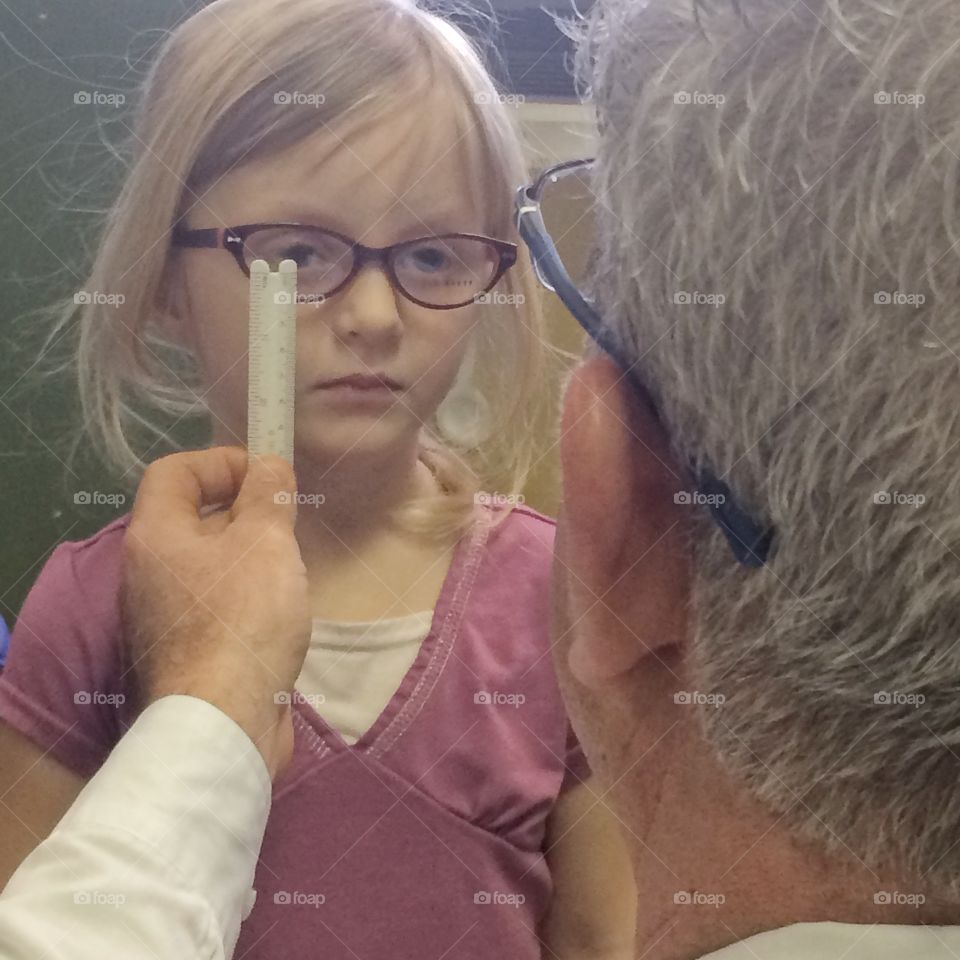 Optometrist checking glasses on young girl