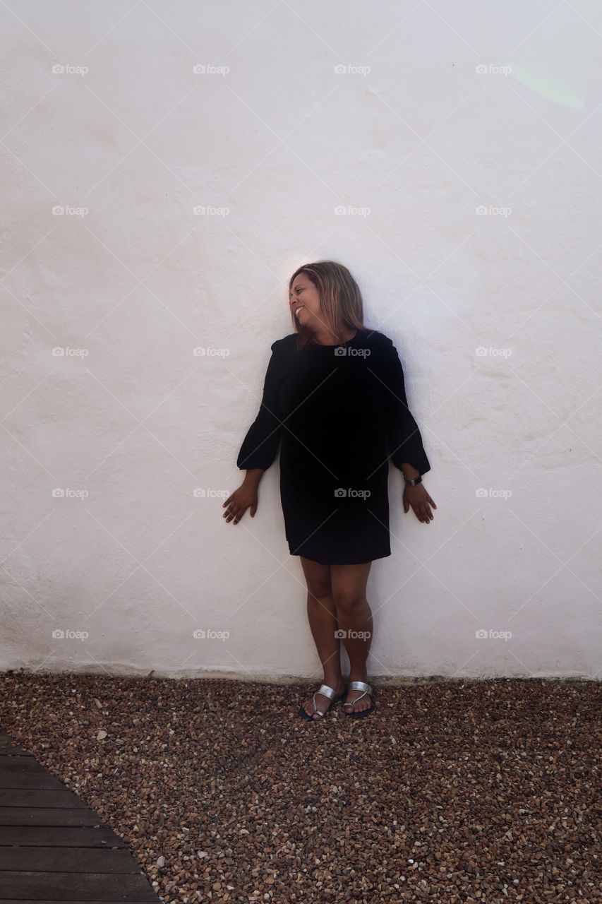 Woman in Black Dress in front of white wall 