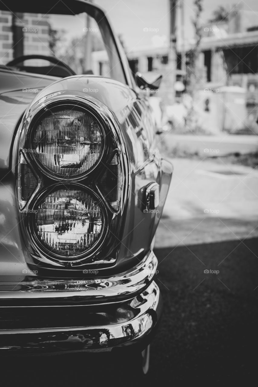 A black and white portrait of the headlights of a traditional American oldtimer car.
